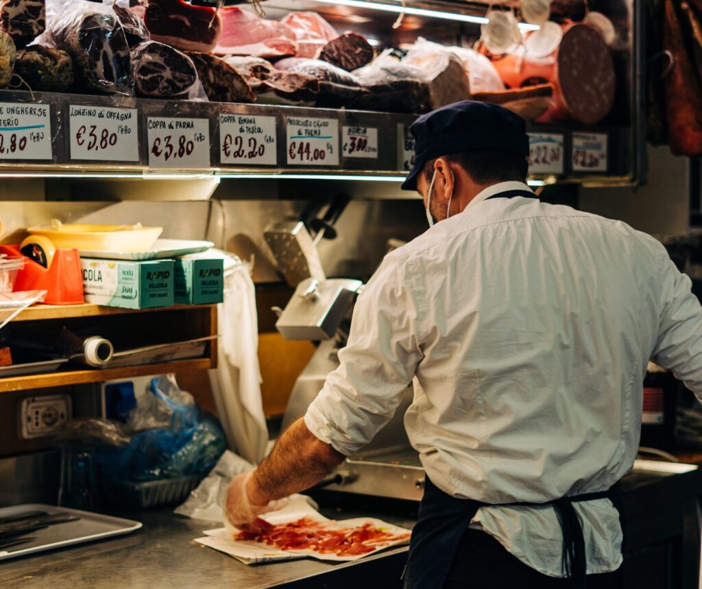 Man cutting slices of prosciutto, a typical Italian ham